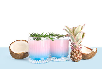 Glasses of cocktail with rosemary, coconut and baby pineapple on table near white wall