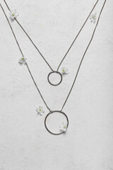 Silver necklaces with flowers on white background, closeup