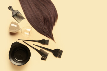 Brown hair with brushes, bowl and hourglass on beige background