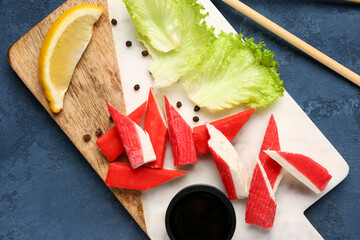 Board with tasty crab sticks on blue background, closeup © Pixel-Shot