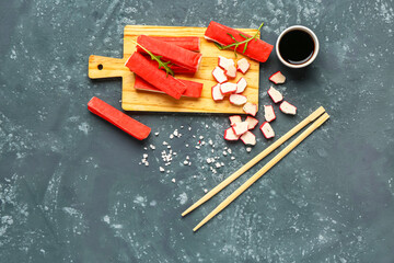 Wooden board with tasty crab sticks and sauce on green background © Pixel-Shot