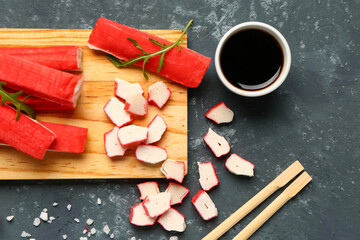 Wooden board with tasty crab sticks and sauce on green background, closeup © Pixel-Shot