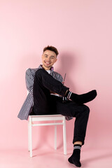 A happy young man sitting with a bottle of coke. fast food and sugar addiction. Isolated on pink background.