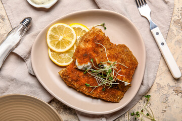 Plate of tasty fried codfish with lemon on grunge background