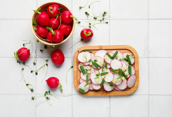 Board and bowl with fresh slices of radish on light tile background