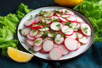 Plate with fresh sliced radish and lettuce on blue grunge background