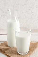 Bottle and glass with fresh milk on light wooden table