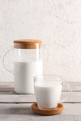 Jug and glass with fresh milk on grey wooden table