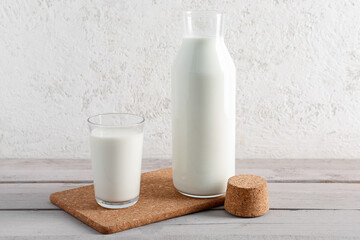 Bottle and glass with fresh milk on grey wooden table