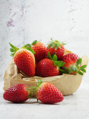 Strawberries on a stone base and inside a kraft paper bag.
