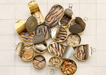 Many opened cans with different fish on tiled table