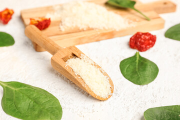 Spoon with tasty grated Parmesan cheese on light background