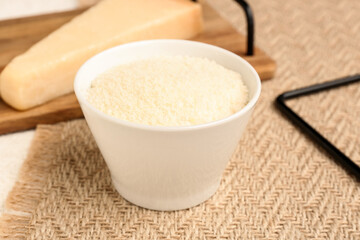 Bowl with tasty grated Parmesan cheese on table