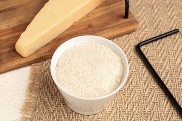 Bowl with tasty grated Parmesan cheese on table