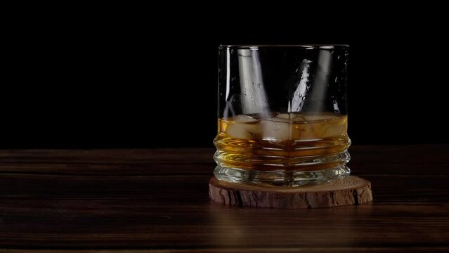 placing a whisky glass on counter top -black background (4k - slow motion)[ high quality colors]
