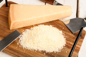 Board with tasty grated Parmesan cheese on light wooden background, closeup