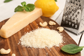 Board with tasty grated Parmesan cheese on light wooden background, closeup