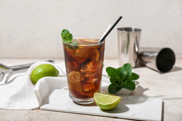 Glass of tasty Cuba Libre cocktail on light background
