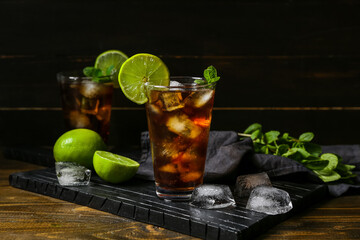 Glasses of tasty Cuba Libre cocktail on dark wooden background