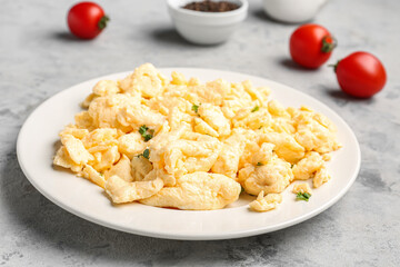 Plate of scrambled eggs and tomatoes on grunge background