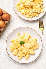 Composition with plates of scrambled eggs on light textured background