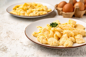 Plates of scrambled eggs on light textured background