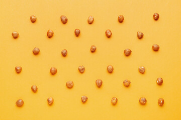 Shelled hazelnuts on orange background, closeup