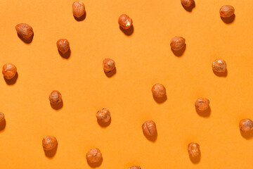 Shelled hazelnuts on orange background, closeup