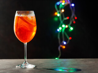 Glass of Aperol Spritz cocktail on a blurred background with colorful lights. Aperol spritz cocktail on the party table. Copy space