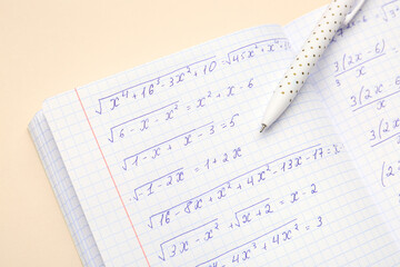 Copybook with maths formulas and pen on beige background