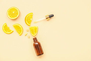 Bottle with pipette and orange pieces on beige background