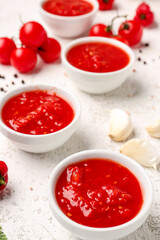 Bowls with tasty tomato sauce on light background