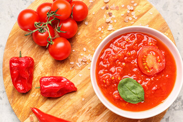 Bowl with tasty tomato sauce and fresh vegetables on grunge background, closeup