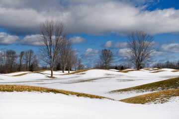 Bare trees and hills in the Ontario countryside with snow in winter