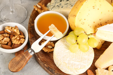 Plate with different types of cheese, honey and grapes on table, closeup