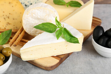 Wooden board with different types of cheese on grunge background, closeup