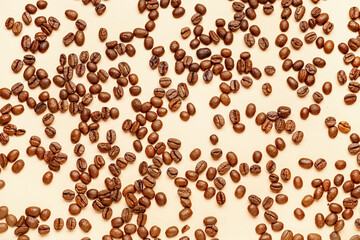 Scattered coffee beans on pale yellow background