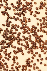 Scattered coffee beans on pale yellow background