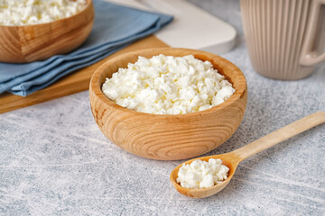 Bowl with tasty cottage cheese on light grunge background
