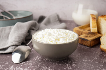 Bowl with tasty cottage cheese on dark grunge background