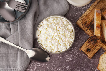 Bowl with tasty cottage cheese on dark grunge background