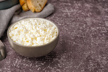 Bowl with tasty cottage cheese on dark grunge background