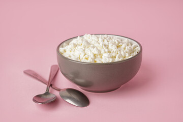 Bowl with tasty cottage cheese on pink background