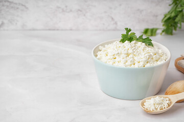 Bowl with tasty cottage cheese and parsley on light background