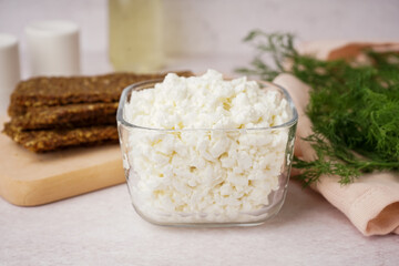 Bowl with tasty cottage cheese on light background