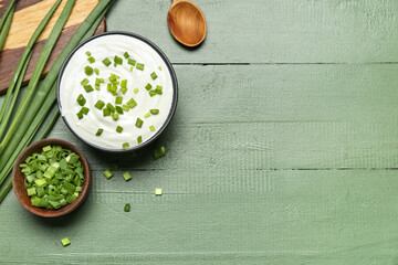 Bowls of tasty sour cream with green onion on color wooden background