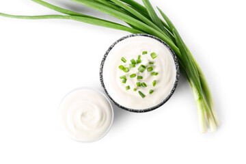 Bowls of tasty sour cream with green onion on white background