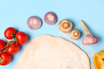 Fototapeta premium Fresh pizza dough with tomatoes, mushrooms, onion, garlic, and bell pepper on blue background, top view