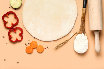 Raw dough and ingredients for preparing vegetable pie on beige background