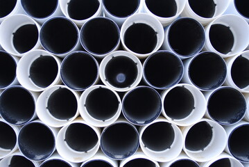 Pile of white and black PVC tubes and pipes abstract background construction site